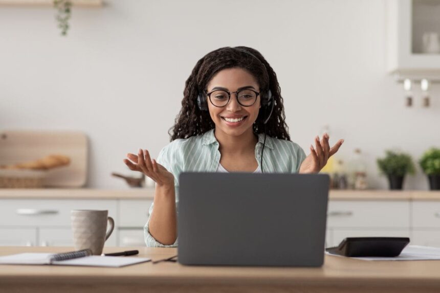 Online teacher working from home, using a laptop and headphones for a video call.