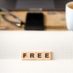 The word "free" spelled out with wooden blocks on a computer desk.