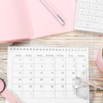 A woman's home office desk, with a calendar and calculator.