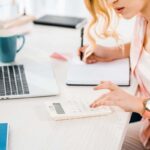 Woman sitting in home office, using a calculator and working on a budget