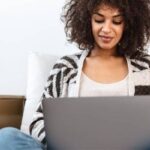 Woman writing on laptop at home.