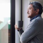 Shot of a senior man drinking coffee and looking thoughtfully out of a window