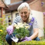 Senior woman potting plant in garden at home