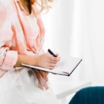 Image of woman working at home office desk and writing in a notebook