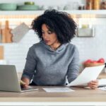 A woman working from home on a laptop in her kitchen.