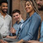 Cheerful young businesspeople with laptop working in office