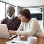 happy senior couple using a laptop in their living room to look at their financial budgets