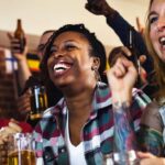 Diverse group of friends cheering sport at bar together