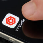 Touching top open Youtube Studio app icon with finger on iphone 15 pro max close up view