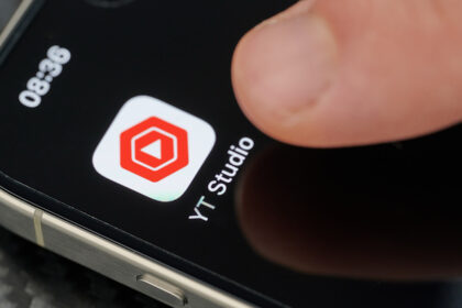 Touching top open Youtube Studio app icon with finger on iphone 15 pro max close up view