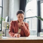 A remote human resources professional working from home office and writing in a notebook.