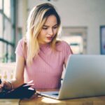 A virtual assistant working from home at her kitchen table and using a laptop.