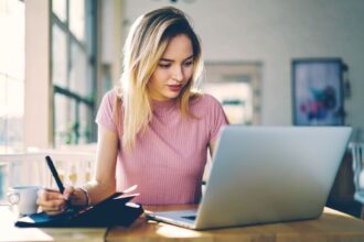 A virtual assistant working from home at her kitchen table and using a laptop.