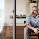 pensive bearded business man sitting on chair looking out of the window