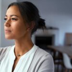 Young mixed-race woman looking out of the window with a look of consternation on her face