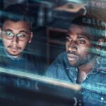 Concept of two young professional men looking at a screen in a technological data centre