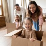 Happy parents playing with little kids riding in box