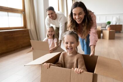 Happy parents playing with little kids riding in box