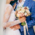 Close up image of a wedding ceremony, with a bride and groom holding flowers.