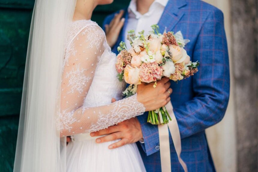 Close up image of a wedding ceremony, with a bride and groom holding flowers.