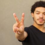 A young black man makes the symbol of a peace sign with two fingers