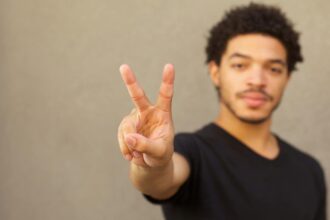 A young black man makes the symbol of a peace sign with two fingers