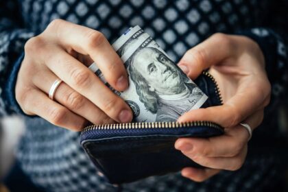 An upclose image of a woman's hands holding a wallet and counting money.