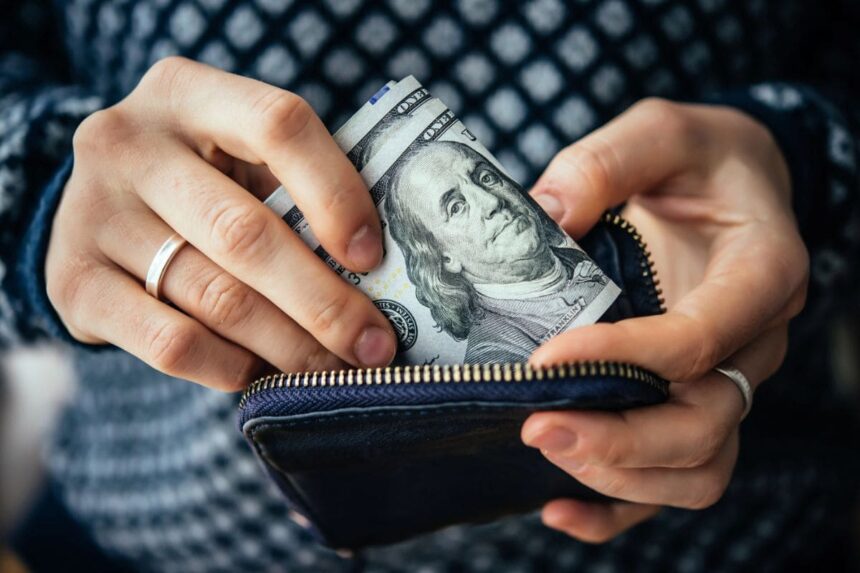 An upclose image of a woman's hands holding a wallet and counting money.