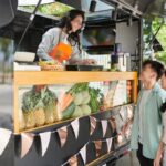 A woman working at a food truck, taking orders through the window.