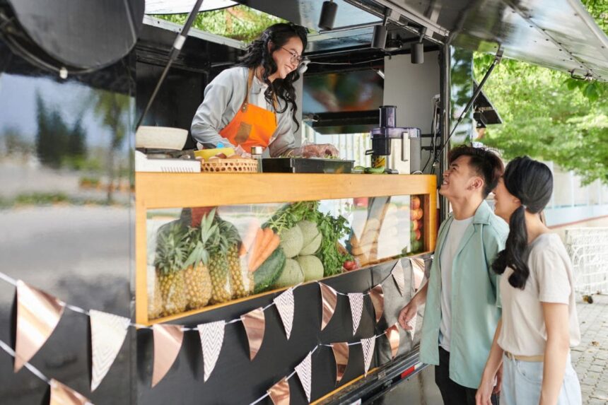 A woman working at a food truck, taking orders through the window.